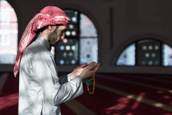 Young Arabic Muslim man  praying. Doing a dailly pray inside modern beautiful mosque.