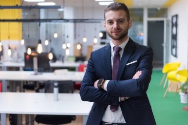 Ekibi arka plandayken başarılı bir iş adamı pozu veriyor..