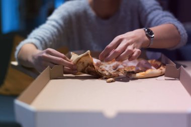 Güzel bir kadın pizza yiyip kola içerken gecenin geç saatlerinde Expres restoranında oturuyor..