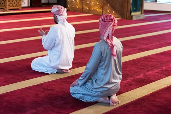 2人の多民族の宗教的なイスラム教徒の若者が一緒にコーランを祈り 読んでいます モスクで祈るイスラム教徒のグループ — ストック写真