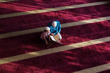 Müslüman baba ve oğul birlikte dua ediyorlar. Müslüman baba ve oğul camide namaz kılıyor ve camide Kuran okuyorlar..