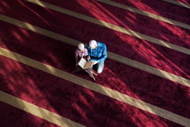 Müslüman baba ve oğul birlikte dua ediyorlar. Müslüman baba ve oğul camide namaz kılıyor ve camide Kuran okuyorlar..
