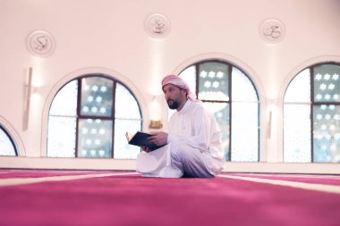 Genç Arap Müslüman adam Kuran okuyup dua ediyor. Camide Kur 'an okuyan dindar Müslüman adam..