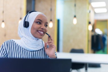 Türbanlı Afrikalı Müslüman kadın. Müşteri temsilcisi. Telefon kulaklıklı iş kadını..