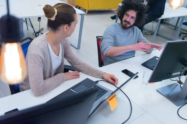 Business team working on new project and smiling. Man and woman sitting together in modern office for project discussion.