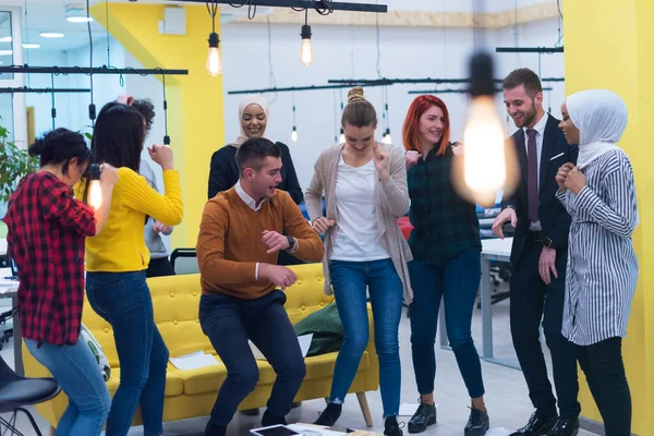 Genç iş adamları ofiste iyi bir işi kutluyorlar. İş bittikten sonra iş yerinde dans eden bir grup genç iş arkadaşı başarılı bir şekilde.