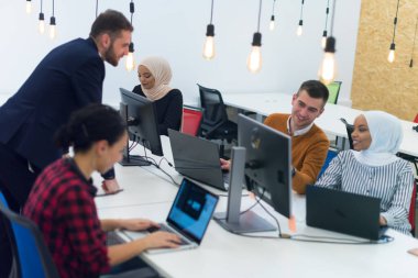 Modern ofisteki çok ırklı, yaratıcı genç insanlar. Bir grup genç iş adamı dizüstü bilgisayar, tablet, akıllı telefon ve defterle birlikte çalışıyor. Birlikte çalışan başarılı bir hipster takımı. Bağımsızlar.