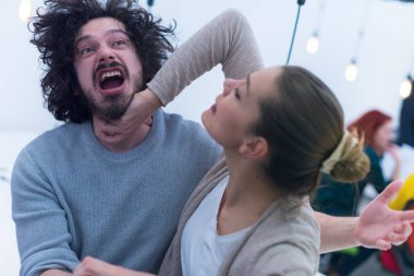 İki yaratıcı ofis çalışanı, ofis içinde çalışırken birbirleriyle şakalaşarak iş birliği yaparlar..