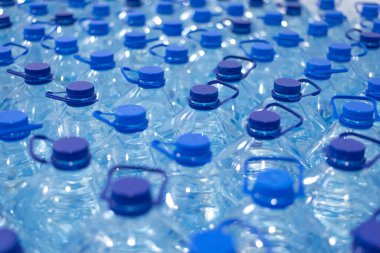 Temiz, serin, doğal suyla dolu bir sürü şişe. Sırayla su standı olan bir grup plastik şişe..