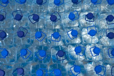 Temiz, serin, doğal suyla dolu bir sürü şişe. Sırayla su standı olan bir grup plastik şişe..