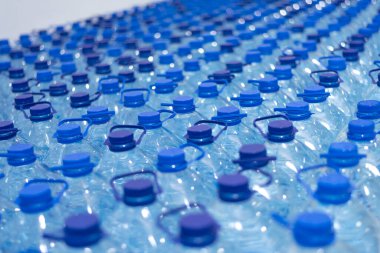 Temiz, serin, doğal suyla dolu bir sürü şişe. Sırayla su standı olan bir grup plastik şişe..