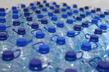 Temiz, serin, doğal suyla dolu bir sürü şişe. Sırayla su standı olan bir grup plastik şişe..