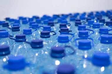 Temiz, serin, doğal suyla dolu bir sürü şişe. Sırayla su standı olan bir grup plastik şişe..