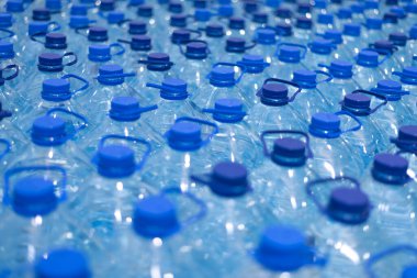 Temiz, serin, doğal suyla dolu bir sürü şişe. Sırayla su standı olan bir grup plastik şişe..
