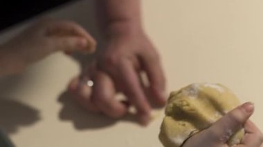 Mutfak masasında annesiyle bisküvi yapan küçük bir kızın ellerini kapat.