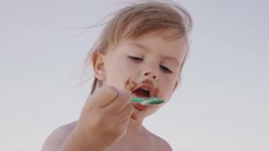 Tatlı küçük kız sahilde dondurma yiyor, ağır çekimde.