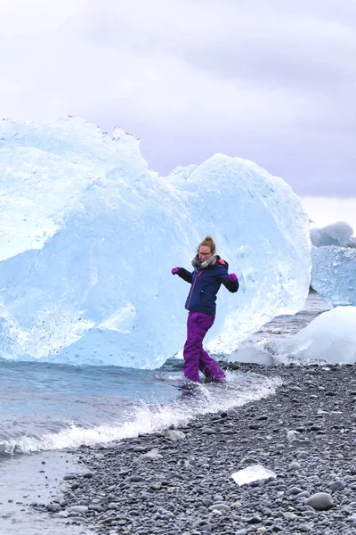 Νεαρή γυναίκα ταξιδιώτης ταξιδεύει στην παραλία Diamond στην Ισλανδία. Κατεψυγμένος πάγος στην παραλία με μαύρη άμμο που είναι γνωστό ρέει από το Jokulsarlon όμορφη λιμνοθάλασσα παγόμορφου στο εθνικό πάρκο Vatnajokull, Νοτιοανατολική Ισλανδία, Ευρώπη — Φωτογραφία Αρχείου