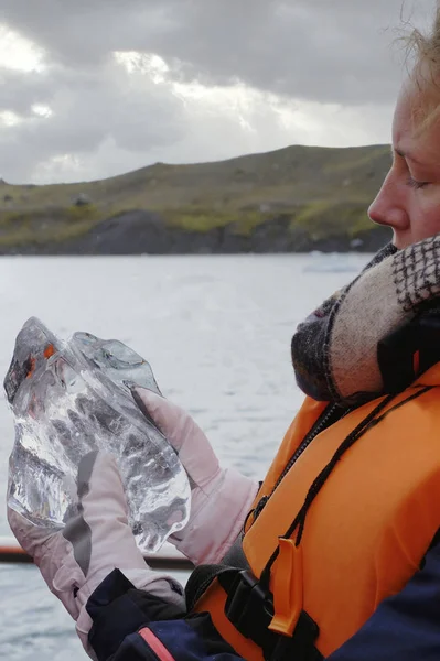 Jeune femme fait une excursion en bateau à Jokulsarlon Glacier Lagoon en Islande. Elle tient un gros morceau de glace — Photo