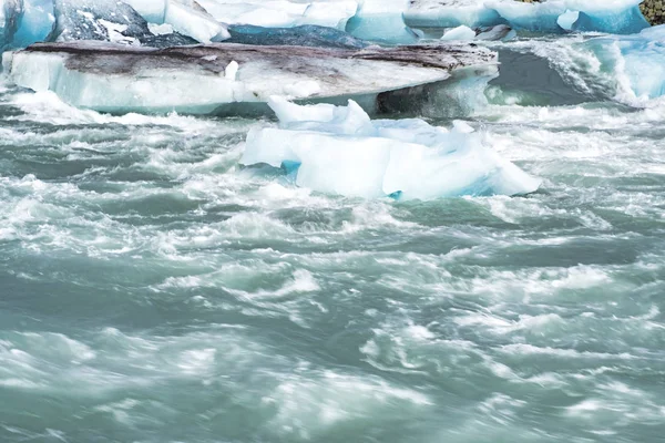 Icebergs flutuando na água fria da lagoa glacial Jokulsarlon. Parque Nacional Vatnajokull, no sudeste da Islândia, durante uma viagem de carro — Fotografia de Stock