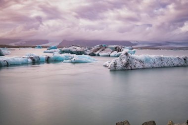 İzlanda 'da Jokulsarlon Buzul Gölü. Uzun pozlu çekim suyu ve gökyüzünü ipeksi yapar. Uzun pozlama, buzul, karamsar kavramlar