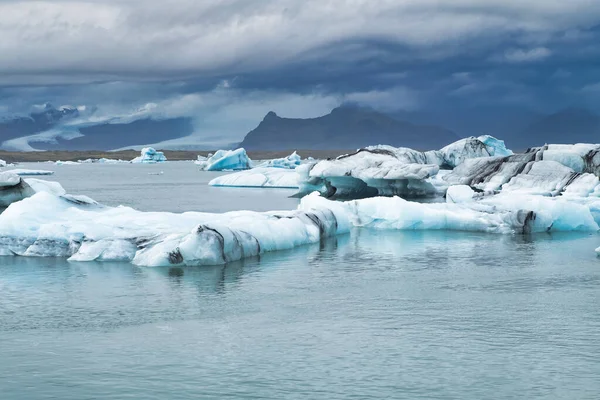 Icebergs flutuando na água fria da lagoa glacial Jokulsarlon. Parque Nacional Vatnajokull, no sudeste da Islândia, durante uma viagem de carro — Fotografia de Stock