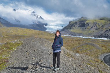 One woman is smiling at camera, the highlands and the glacier and the moss covered mountains in background, Iceland