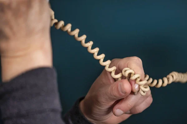 Old retro, old fashioned white telephone cord against green background, woman hand holding telephone cord — Stock Photo, Image