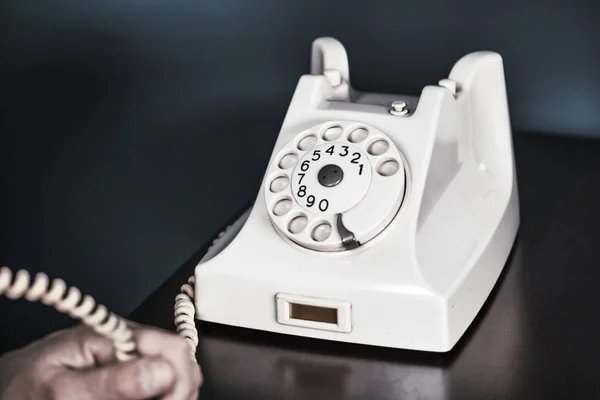 Phone old retro, old fashioned white telephone against green background, woman hand holding telephone cord — Stock Photo, Image