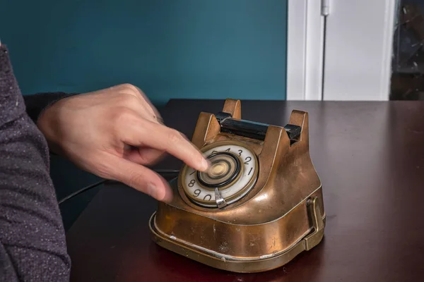 Retro antique classic outdated copper with black color rotary telephone from circa 1950s on wooden table, green wall background. Vintage old style photo in long exposure — Stock Photo, Image
