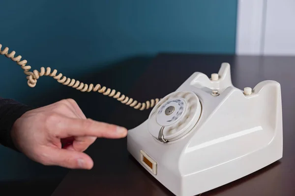 Phone old retro, old fashioned white telephone against green background, woman hand holding telephone cord in long exposure — Stock Photo, Image