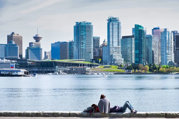 Vancouver - květen 05 2019: Centrum Vancouveru, Kanada.Pohled na centrum Vancouveru, ze Stanley parku, dva lidé leží na nábřeží — Stock fotografie