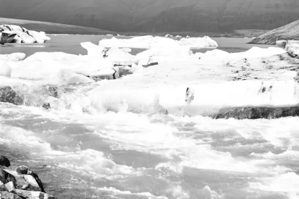 Айсберги плавают в холодной воде ледниковой лагуны Джоколсарлон. Национальный парк Ватнайокулл, на юго-востоке Исландии во время дорожной поездки, винтажные черно-белые — стоковое фото