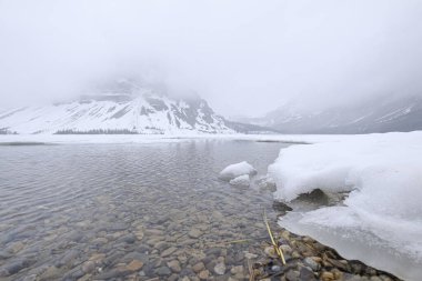 Karla kaplı dağlarla çevrili sakin bir göl manzarası, Jasper, Kanada