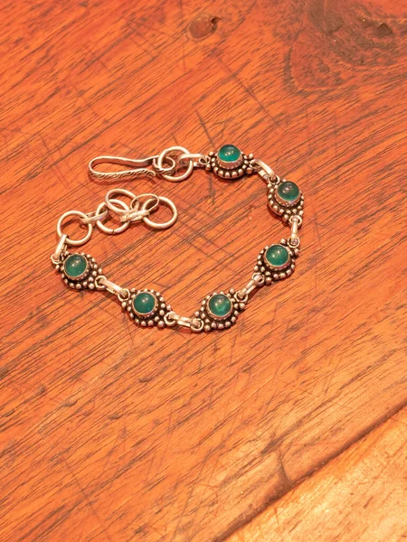 Armband aus grünem Onyx-Perlen in Silber, isoliert auf Holztischhintergrund — Stockfoto