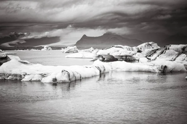 IJsbergen drijven in het koude water van de Jokulsarlon gletsjerlagune. Nationaal park Vatnajokull, in het zuidoosten van IJsland tijdens een road trip, vintage zwart-wit — Stockfoto