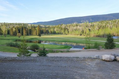 Mavi gökyüzü ve bulutlu golf sahası, kayalar ön planda, Clearwater Kanada