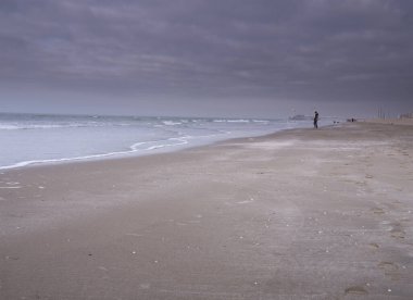 Scheveningen, Şubat 18 2019: Scheveningen, Lahey, Hollanda. Yumuşak renkli deniz manzarası, plaj manzarası, sahilde duran yalnız çocuk. Hollanda 'da.