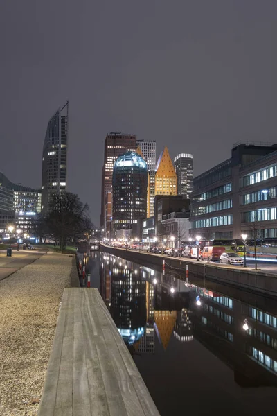 Haia, Países Baixos - 18 de fevereiro de 2019: Skyline de Haia à noite com canal em frente e edifícios altos, Castalia, Helicon, Zurichtoren e o Muzentoren em segundo plano — Fotografia de Stock