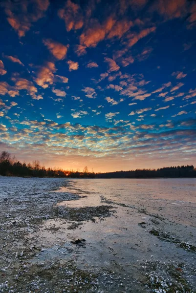 Een koude zonsondergang in de winter op een bevroren meer met een prachtige lucht en zonnestralen op de achtergrond Friesland, Nederland — Stockfoto