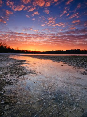 Donmuş bir gölün üzerinde soğuk bir günbatımı güzel bir gökyüzü ve arka planda güneş ışınları Hollanda, Friesland 'da