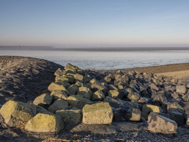 Hollanda 'nın Friesland Eyaleti' ndeki Waddensea 'da deniz üzerinde ufuk manzarası, ön planda kayalar, ulusal park ve Unesco Dünya mirası alanı