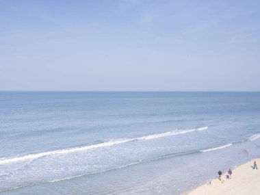 Scheveningen, Şubat 18 2019: Scheveningen, Lahey, Hollanda. Yumuşak renkli deniz manzarası, sahil manzarası, sahilde yürüyen insanlar. Hollanda 'da.
