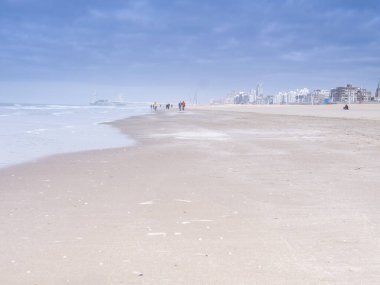 Scheveningen, Şubat 18 2019: Scheveningen, Lahey, Hollanda. Yumuşak renkli deniz manzarası, sahil manzarası, sahilde yürüyen insanlar. Hollanda 'da.