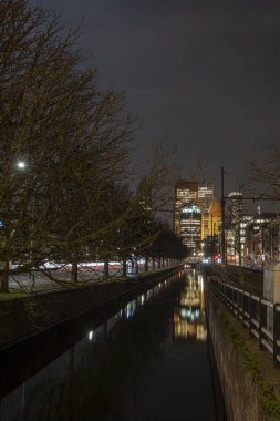 The Hague, the Netherlands - 18 February 2019: Skyline of The Hague at night with canal in front and high buildings , Castalia, Helicon, Zurichtoren and the Muzentoren in background