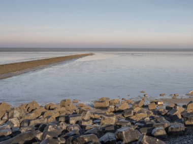Hollanda 'nın Friesland Eyaleti' ndeki Waddensea 'da deniz üzerinde ufuk manzarası, ön planda kayalar, ulusal park ve Unesco Dünya mirası alanı