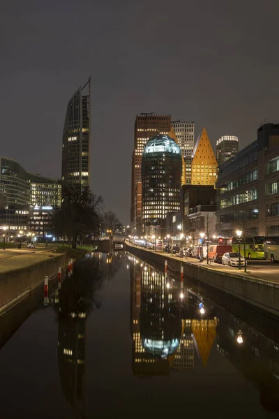 Haia, Países Baixos - 18 de fevereiro de 2019: Skyline de Haia à noite com canal em frente e edifícios altos, Castalia, Helicon, Zurichtoren e o Muzentoren em segundo plano — Fotografia de Stock