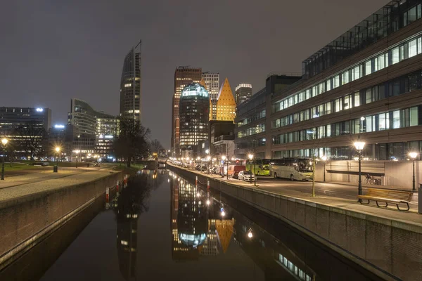 Haia, Países Baixos - 18 de fevereiro de 2019: Skyline de Haia à noite com canal em frente e edifícios altos, Castalia, Helicon, Zurichtoren e o Muzentoren em segundo plano — Fotografia de Stock