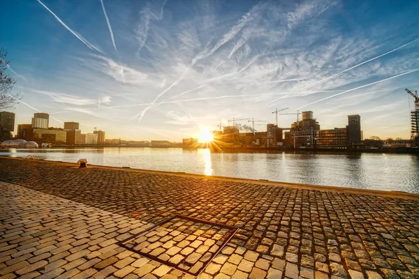 Rotterdam - 14 February 2019: Rotterdam, The Netherlands The sun rises behind several old industrial buildings on the waterfront early in the morning, downtown skyline, South Holland, Rotterdam — Stock Photo, Image