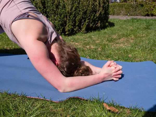 Mujer joven haciendo ejercicios de yoga en el jardín en casa, en pose de delfín — Foto de Stock