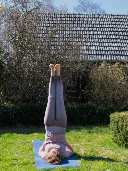 Mujer joven haciendo ejercicios de yoga en el jardín en casa — Foto de Stock